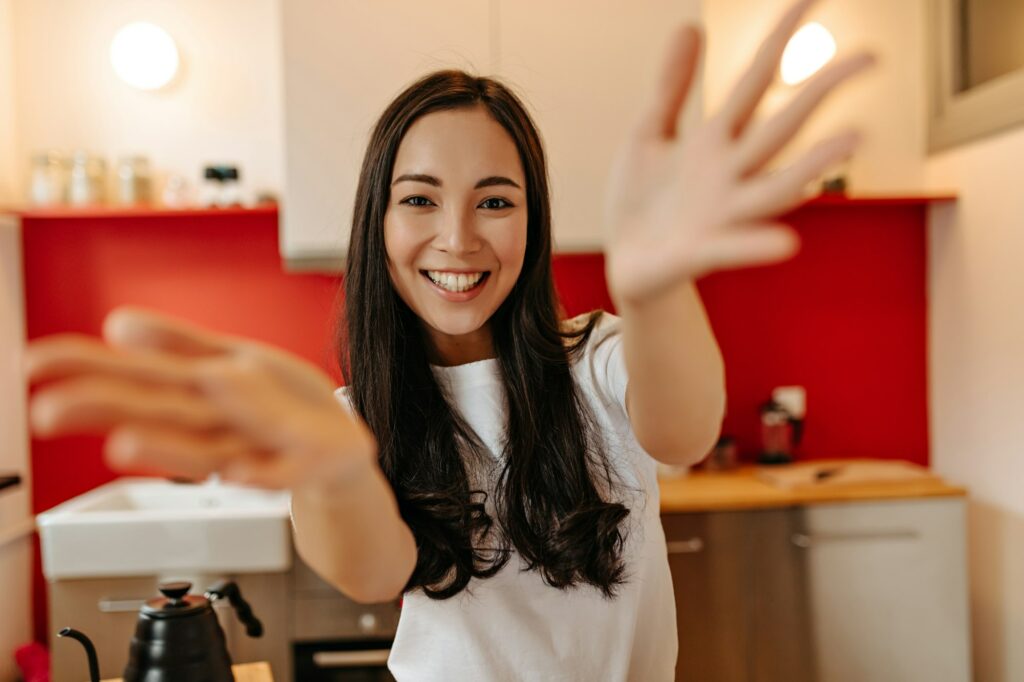 Woman in great mood looks into camera, laughs and claps. Snapshot of girl in white T-shirt in kitch